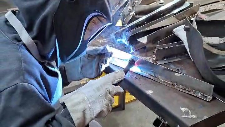 Soldador trabalhando com a tocha, faíscas saindo da peça
